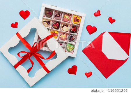 Red envelope with candy and gift box and Valentines hearts on colored background. Flat lay, top view. Romantic love letter for Holiday concept Red envelope with candy and gift box and Valentines hearts on colored background. Flat lay, top view. Romantic love letter for Holiday concept 116631295