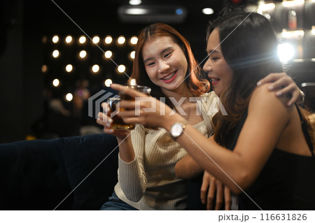 Cheerful Asian female friends having fun hanging out at a stylish bar. Nightlife and friendship concept 116631826