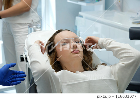 female dentist examining young girl patient's teeth at dental clinic. Doctor probing teeth with dental instrument using an explorer look for cavities treatment and checking problems with filling 116632077