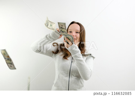 Throwing around dollars Teen throwing around dollar bills. Full length portrait of wasteful rich girl on orange background. Vertical frame 116632085