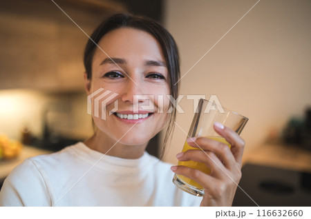 Pretty young woman with a glass of orange juice in hands Pretty young woman with a glass of orange juice in hands 116632660
