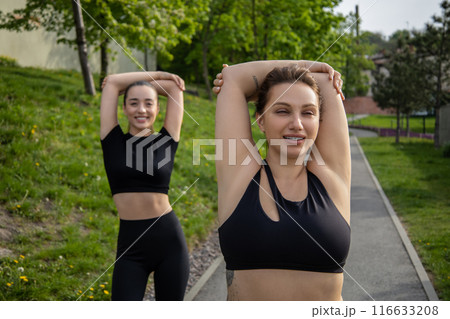 Obese woman with trainer doing arm muscle stretching during workout Obese woman with trainer doing arm muscle stretching during workout 116633208