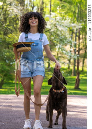 Slim young woman in shorts on a walk with her dog in the park Slim young woman in shorts on a walk with her dog in the park 116633238