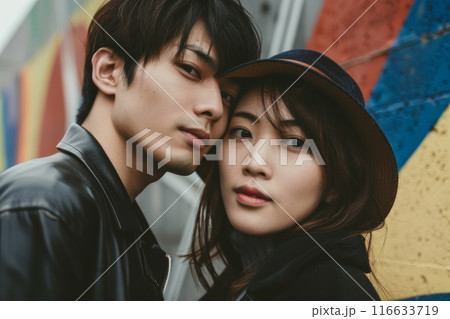 カラフルな壁の前でポーズをとる若いカップルの写真（ポートレート・恋人・ポートレート・インスタ映え） 116633719