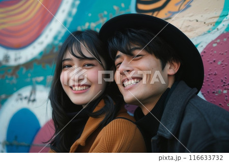 カラフルな壁の前でポーズをとる若いカップルの写真（ポートレート・恋人・ポートレート・インスタ映え） 116633732
