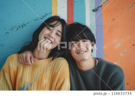 カラフルな壁の前でポーズをとる若いカップルの写真（ポートレート・恋人・ポートレート・インスタ映え） 116633734