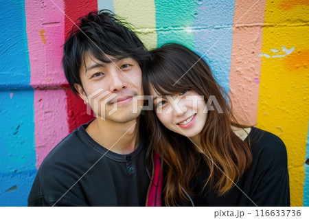 カラフルな壁の前でポーズをとる若いカップルの写真（ポートレート・恋人・ポートレート・インスタ映え） 116633736