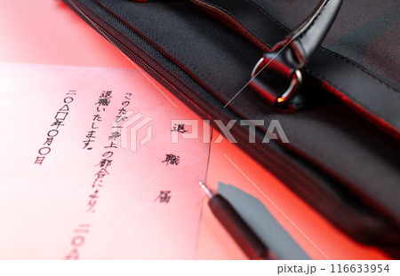 白いテーブルに置かれた手書きの退職届とゲルインクの黒ペンと黒いビジネズバッグの一部を赤い照明で。 白いテーブルに置かれた手書きの退職届とゲルインクの黒ペンと黒いビジネズバッグの一部を赤い照明で。 116633954