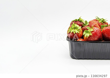 Strawberries in a dark plastic container against white background. Sweet and beautiful berry in a plastic container. Strawberries for sale. Strawberries in a dark plastic container against white background. Sweet and beautiful berry in a plastic container. Strawberries for sale. 116634297