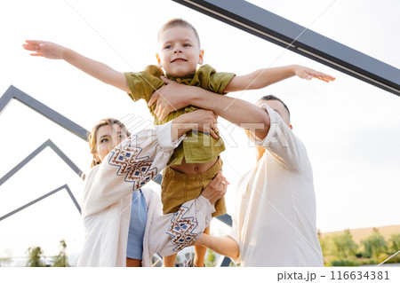 On a Beautiful Sunny Day, Parents Enjoy Lifting Their Child up in the Air, Creating Joyful Memories That Will Last a Lifetime 116634381