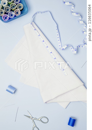 Composition with various threads and sewing accessories on blue background. Top view, copy space 116635064