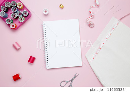 Composition with various threads and sewing accessories on pink background. Mock up notebook 116635284