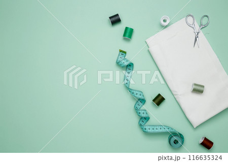 Composition with various threads and sewing accessories on green background. Top view, copy space Composition with various threads and sewing accessories on green background. Top view, copy space 116635324