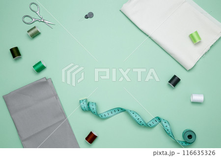Composition with various threads and sewing accessories on green background. Top view, copy space 116635326