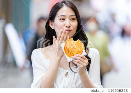 観光をしながら食べ歩きをする若い女性 観光をしながら食べ歩きをする若い女性 116636238