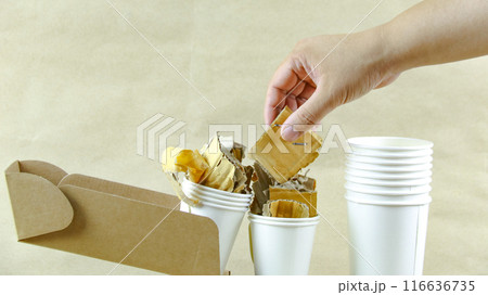 White paper coffee cup, used paper, and cardboard box on a brown surface, awaiting recycling. 116636735
