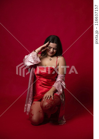 Curvy girl in red nightgown for studio portraits 116637157