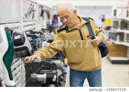 Senor man pensioner buying Upright Vacuum Cleaner in showroom of electrical appliance store 116637219