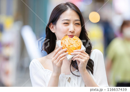 観光をしながら食べ歩きをする若い女性 観光をしながら食べ歩きをする若い女性 116637439