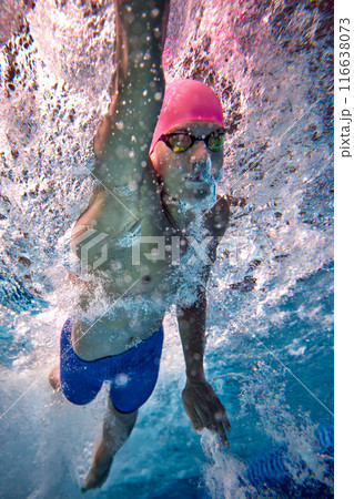 Intensity of swimming. Sportsman swimming freestyle, his body streamlined and focused underwater in pool. Preparing to competition. Intensity of swimming. Sportsman swimming freestyle, his body streamlined and focused underwater in pool. Preparing to competition. 116638073