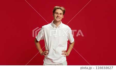 Portrait of young smiling guy, wearing white polo shirt, expressing positivity and confidence against red studio background Portrait of young smiling guy, wearing white polo shirt, expressing positivity and confidence against red studio background 116638627