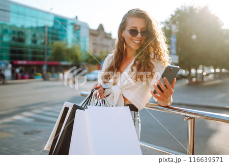 Beautiful woman with shopping bags makes selfie. Woman walking after shopping. Black friday. 116639571