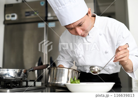厨房で料理を皿に盛る若いアジア人の男性調理師 116639813