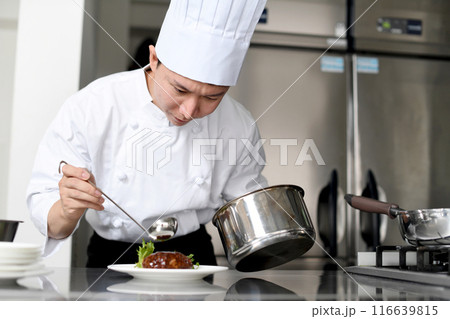厨房で料理を皿に盛る若いアジア人の男性調理師 厨房で料理を皿に盛る若いアジア人の男性調理師 116639815