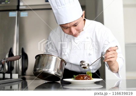 厨房で料理を皿に盛る若いアジア人の男性調理師 116639819