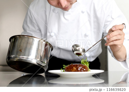 厨房で料理を皿に盛る若いアジア人の男性調理師 116639820