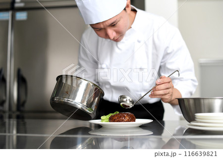厨房で料理を皿に盛る若いアジア人の男性調理師 116639821
