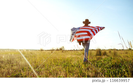 4th of July. American Flag. Traveler with the flag of America. The man in a hat, a backpack, a shirt and jeans. 116639957