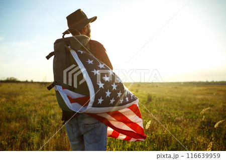 4th of July. American Flag. Traveler with the flag of America. The man in a hat, a backpack, a shirt and jeans. 4th of July. American Flag. Traveler with the flag of America. The man in a hat, a backpack, a shirt and jeans. 116639959
