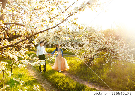 Beautiful loving couple in blooming gardens. Wedding concept. Great sunset light. Lovely newlyweds. 116640173