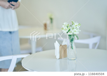 White flowers in a vase on a table on a white background. flower arrangement, space for copying. The unfocused woman next to me. High quality photo White flowers in a vase on a table on a white background. flower arrangement, space for copying. The unfocused woman next to me. High quality photo 116640504