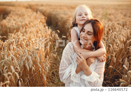 Family in a summer field. Sensual photo. Cute little girl. Woman in a white dress. 116640572