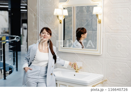 Woman in blue suit adjusts faucet in showroom bathroom Woman in blue suit adjusts faucet in showroom bathroom 116640726
