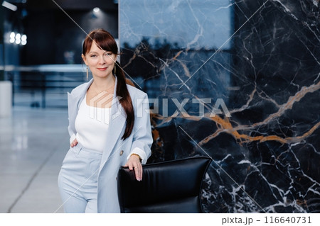 Woman in blue suit standing in front of marble wall 116640731