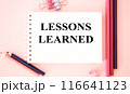 LESSONS LEARNED text on pink background and with pencils.The image shows a slogan Lessons Learnd written on a pink notebook. Bright picture. Concept Image. Can be used as template, signboard, banner 116641123