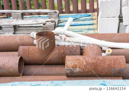 Old rusty metal pipes and white plastic pipes 116642154