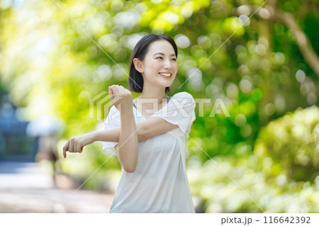 スポーツウエアでストレッチをする笑顔の若い女性 116642392