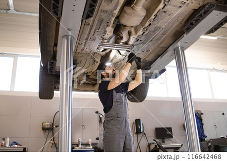 Mechanic working under car on lift in auto repair shop 116642468