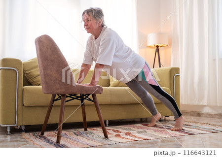 Senior caucasian woman doing yoga at home on chair 116643121
