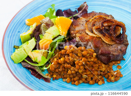 Delicious fried pork with lentils, avocado and orange at plate 116644590