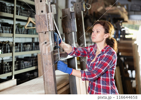 Adult woman processes metal part in workshop Adult woman processes metal part in workshop 116644658