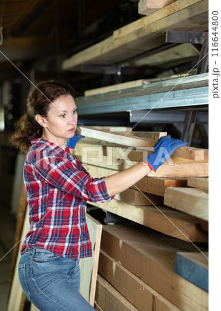Lumber warehouse employee stacks wooden planks in factory Lumber warehouse employee stacks wooden planks in factory 116644800