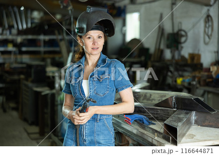During manufacture of product, woman employee works with welding machine During manufacture of product, woman employee works with welding machine 116644871