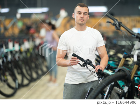 Interested man examining bike handlebar system in store 116644900