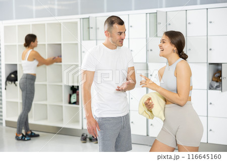 Cheerful man talking with female friend in locker room of climbing gym Cheerful man talking with female friend in locker room of climbing gym 116645160