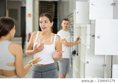Girl enjoying chat with female friend by lockers at climbing gym Girl enjoying chat with female friend by lockers at climbing gym 116645179